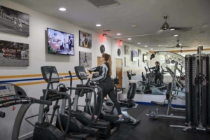 Woman on an elliptical in the gym watching the tv