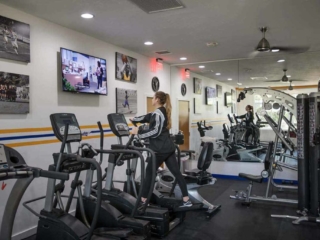 Woman on an elliptical in the gym watching the tv
