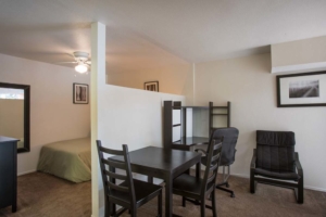 Apartment interior showing the bedroom on the left with a wall divider then the dining table and office area on the right